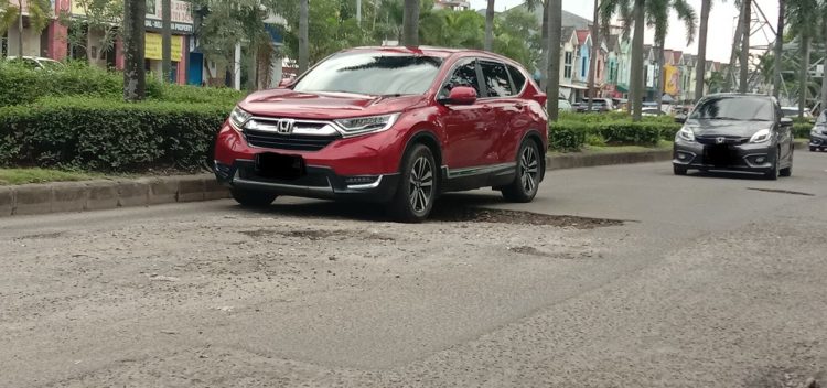 Mobil melintas di jalan berlubang di Jalan Raya Boulevard Gading Seprong, Kelapa Dua, Kabupaten Tangerang. (SOL)